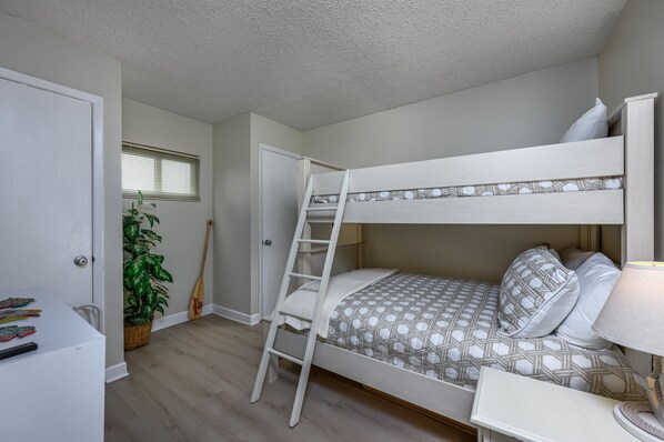 A bunk bed with a ladder, a bedside table, and a lamp.