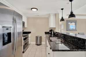 A modern kitchen with a stainless steel refrigerator, a coffee maker, and a sink.