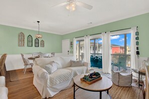 A living room with a white sofa, a round coffee table, and a view of the outside through large windows.