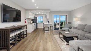 A modern living room with a grey sofa, a wooden bench, and a flat-screen TV. - Beach Retreat, Free Wifi 308A (Oceanside)