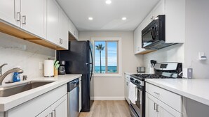 A modern kitchen with white cabinets, a black refrigerator, a stove, and a microwave. - Beach Retreat, Free Wifi 308A (Oceanside)