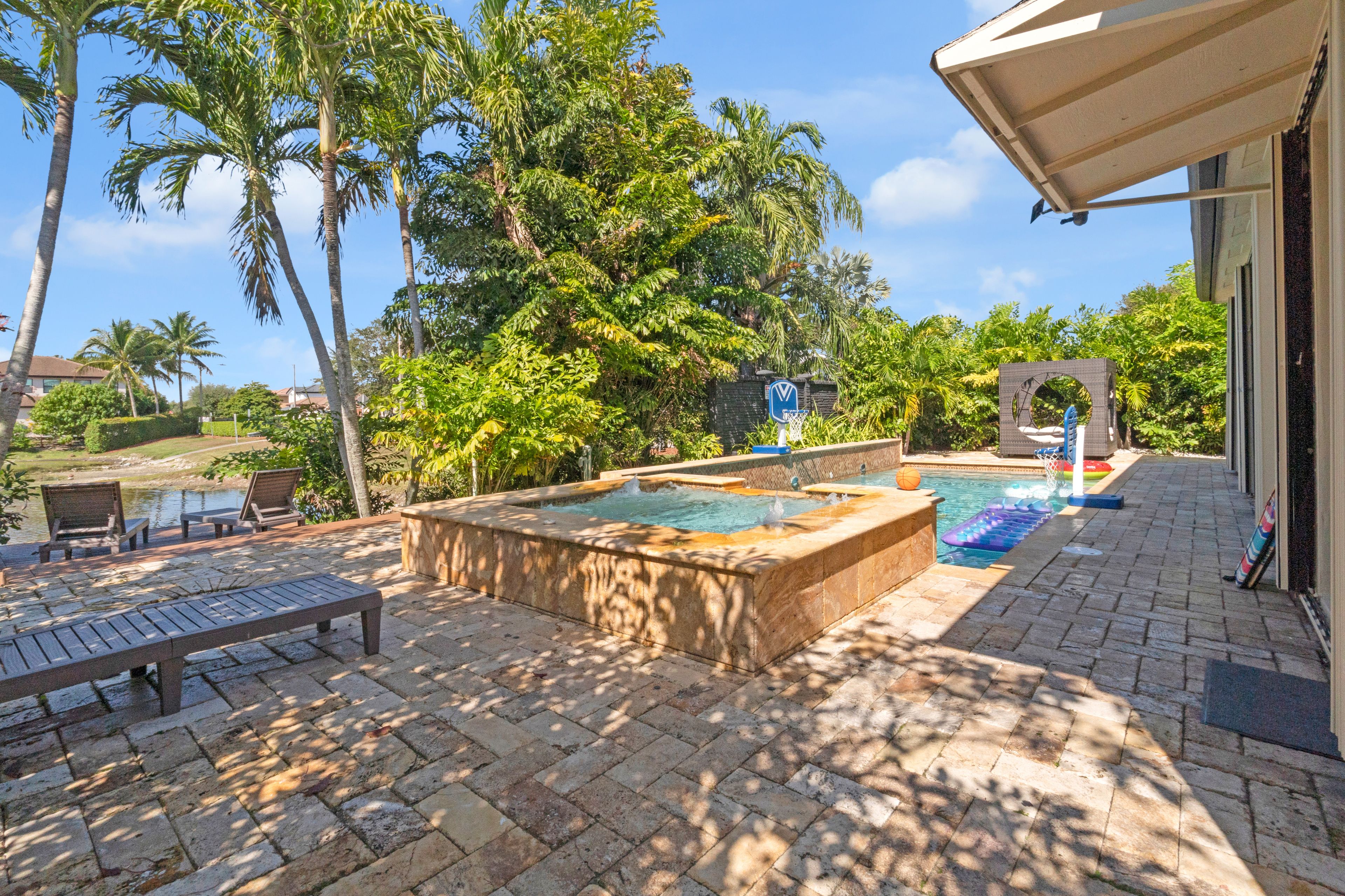 Zona de piscina con jacuzzi, sillas de descanso y una canasta de baloncesto.