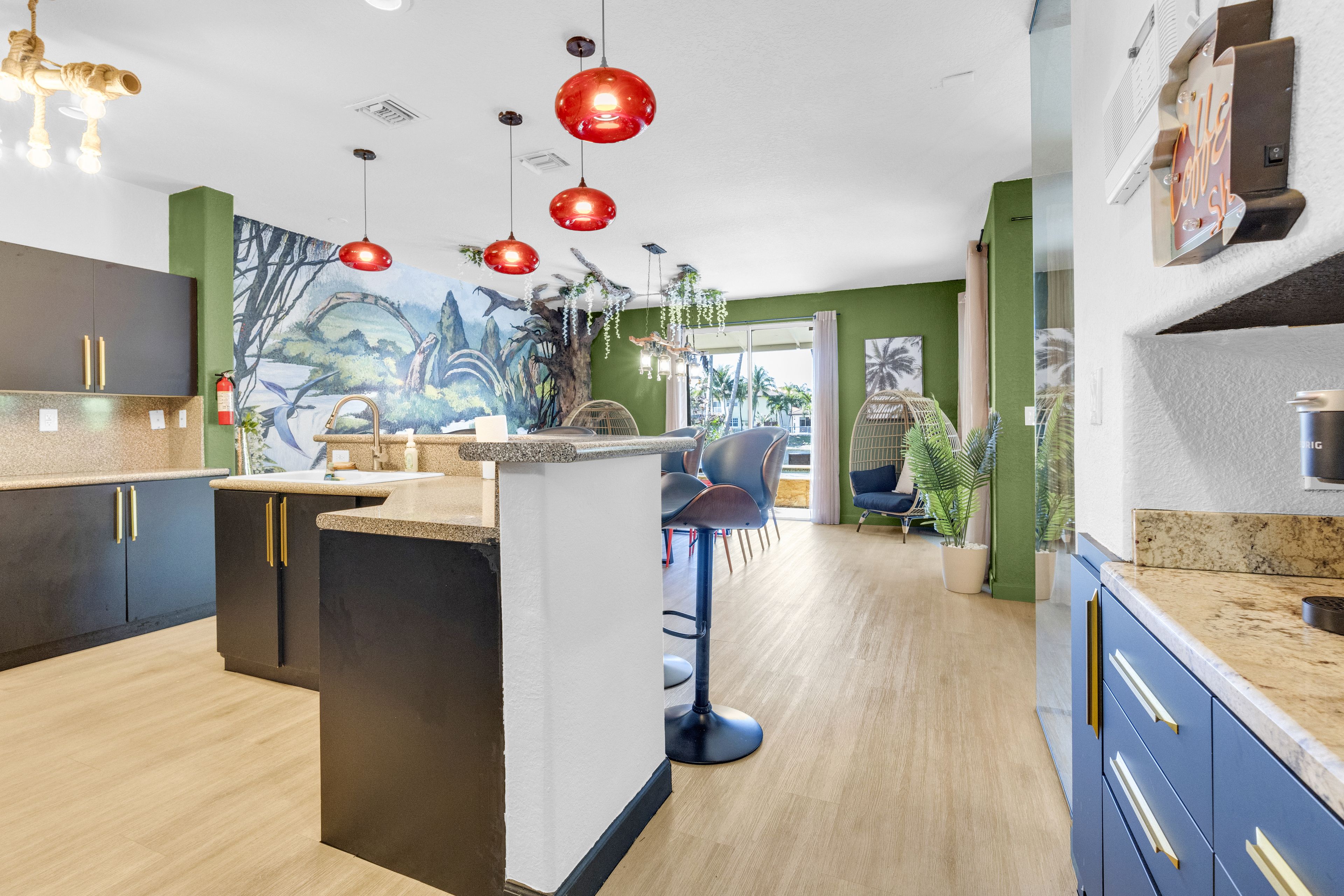 A modern kitchen with a central island, bar stools, and a mural on the wall.