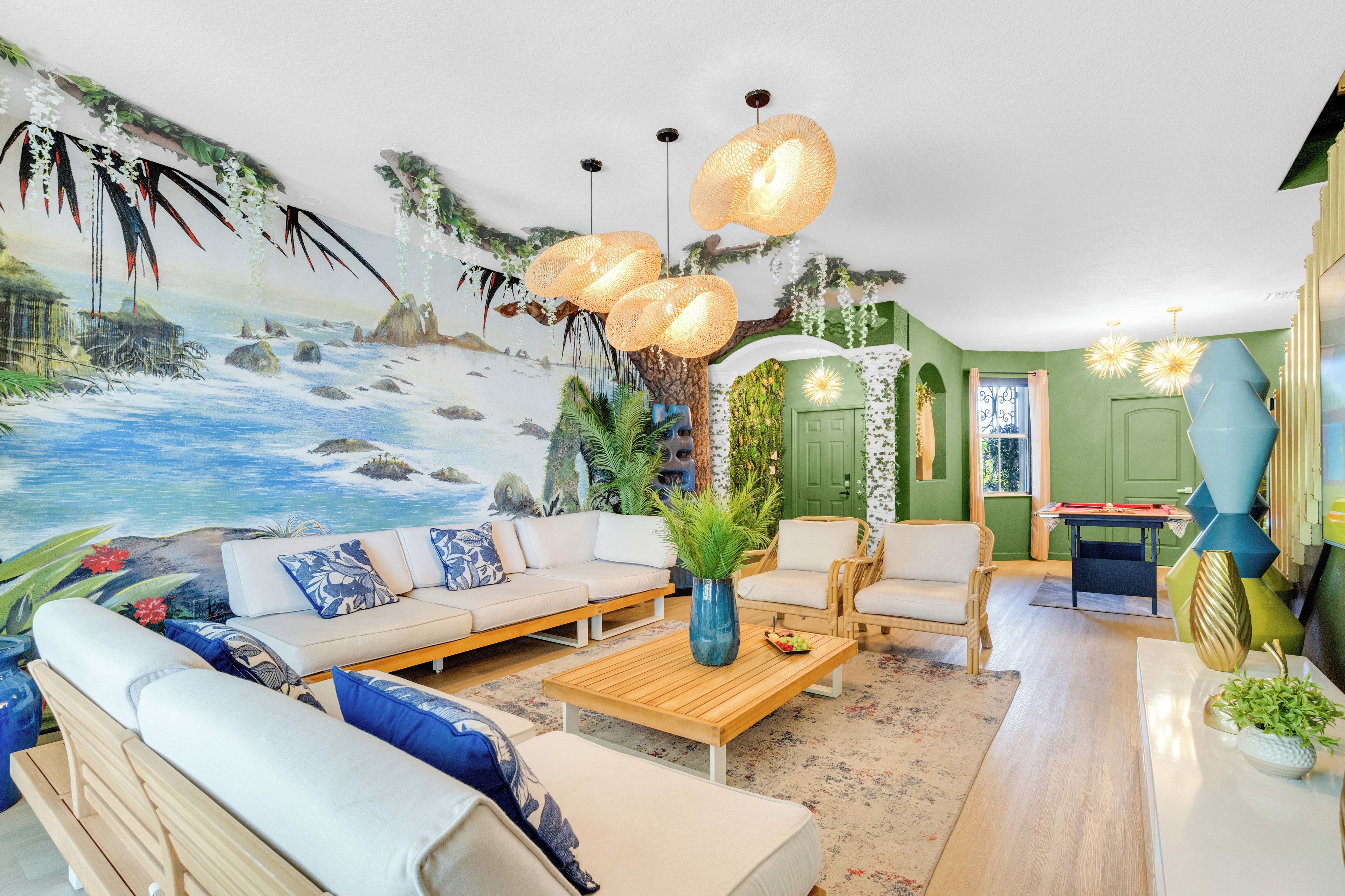 Sala de estar con un mural de playa, un conjunto de sofá, una mesa de centro y una zona de comedor con una mesa y sillas.