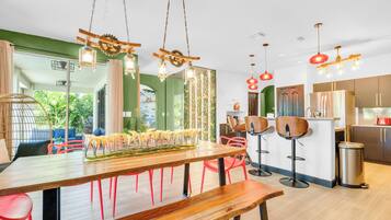Cocina moderna con electrodomésticos de acero inoxidable, una mesa de comedor de madera con sillas rojas y vistas a la vegetación exterior.