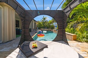 A pool area with a circular viewing structure, a lounge chair, and a fruit tray. - Themed Glow Villa • 4K Cinema • Heated Pool • Lake • Sleeps 12 (Miami)