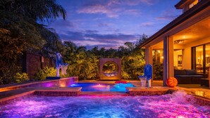 A heated outdoor pool with two basketball hoops, surrounded by lush greenery and a brick wall. - Glow Lakefront Villa, Heated Pool - Spa, 4K Cinema (Miami)