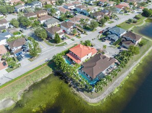 A residential area with houses, a swimming pool, and a body of water. - Themed Glow Villa • 4K Cinema • Heated Pool • Lake • Sleeps 12 (Miami)