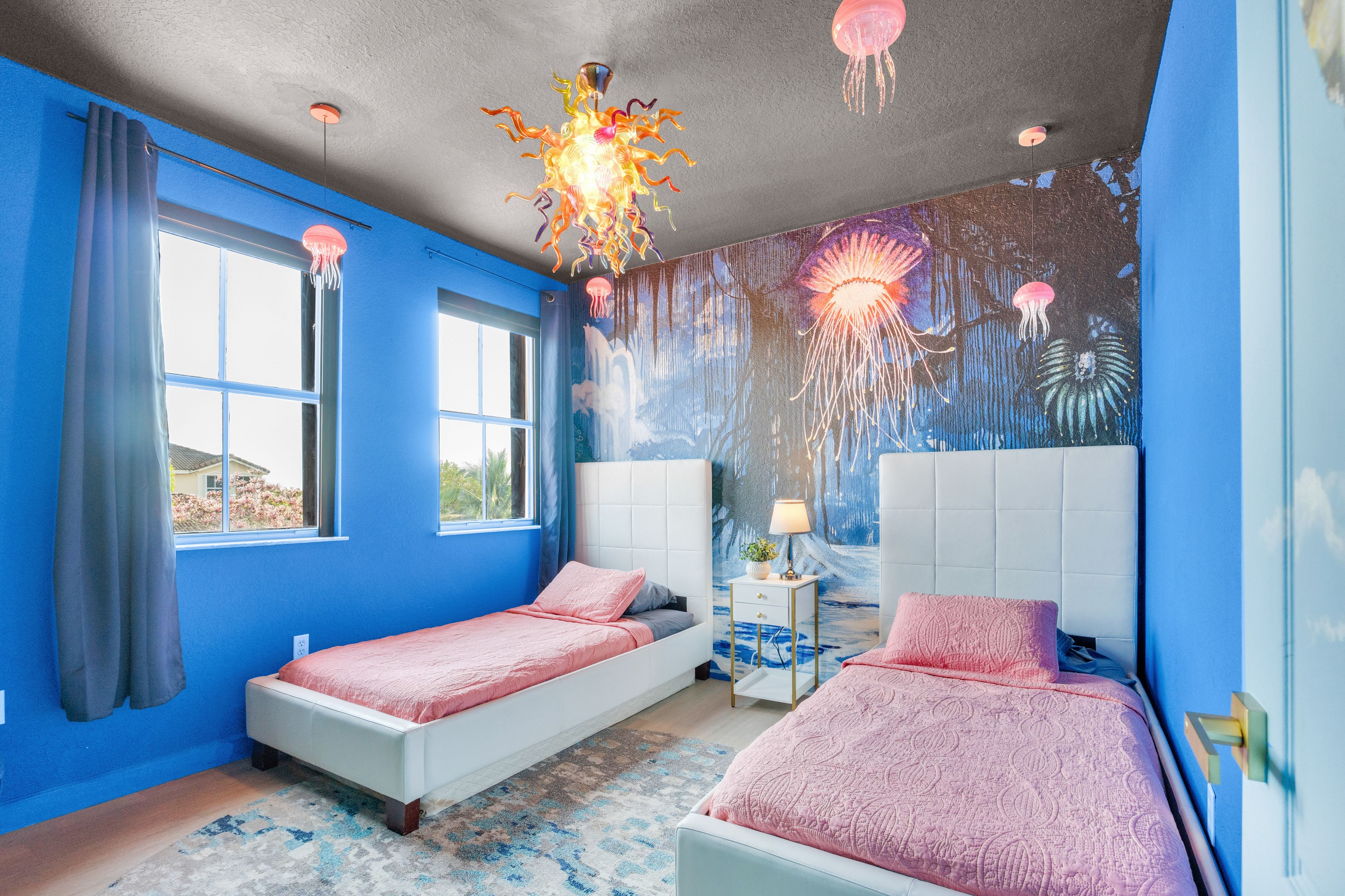 Un dormitorio con dos camas, un mural y una lámpara de techo original.