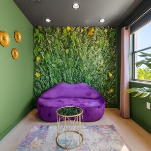 A room with a green wall, a purple bean bag chair, a round gold table, and a patterned rug. - Themed Glow Villa • 4K Cinema • Heated Pool • Lake • Sleeps 12 (Miami)