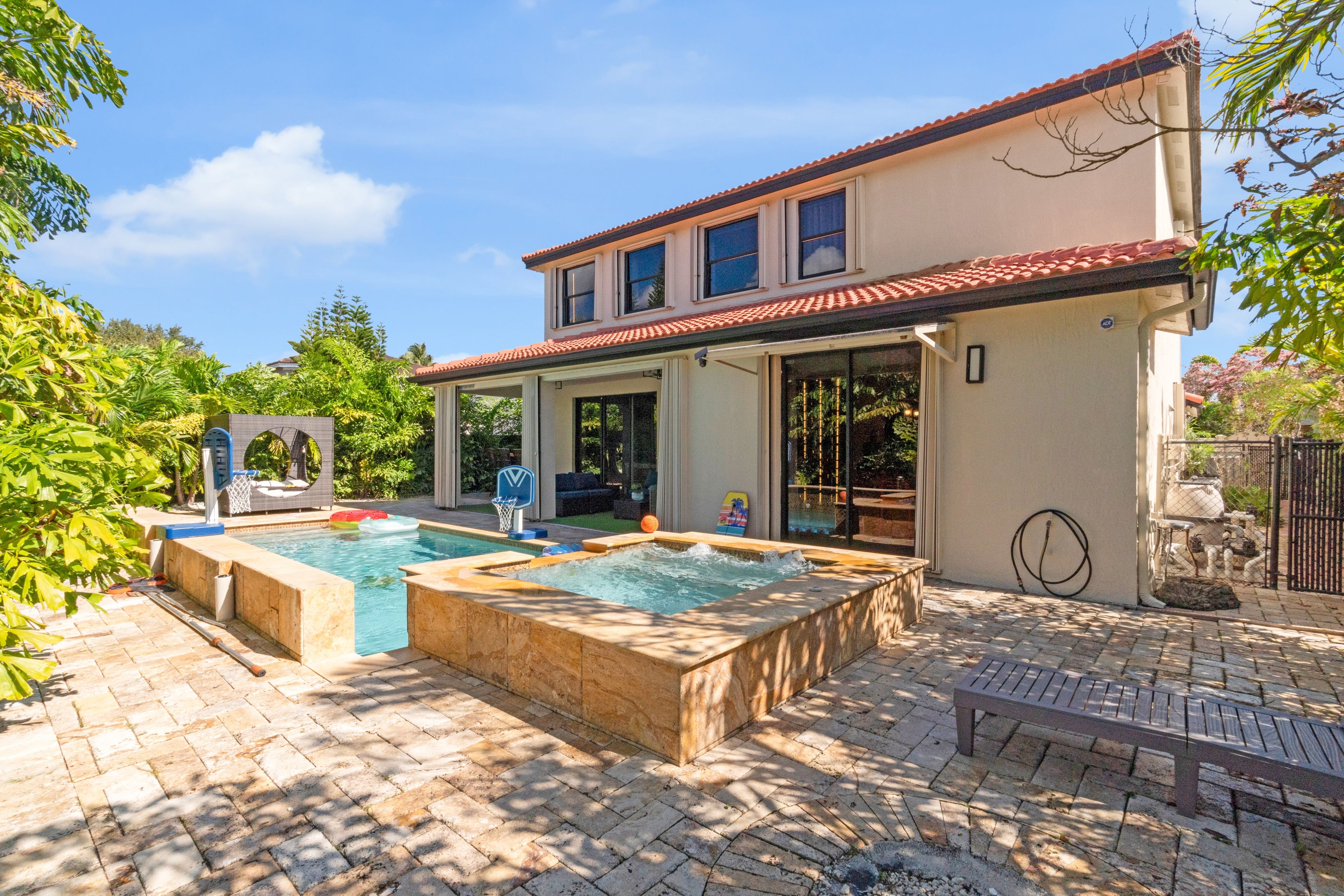 A two-story house with a swimming pool and a hot tub.