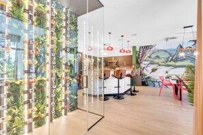 A modern interior with a wall-mounted wine rack, a kitchen area, and a mural. - Themed Glow Villa • 4K Cinema • Heated Pool • Lake • Sleeps 12 (Miami)