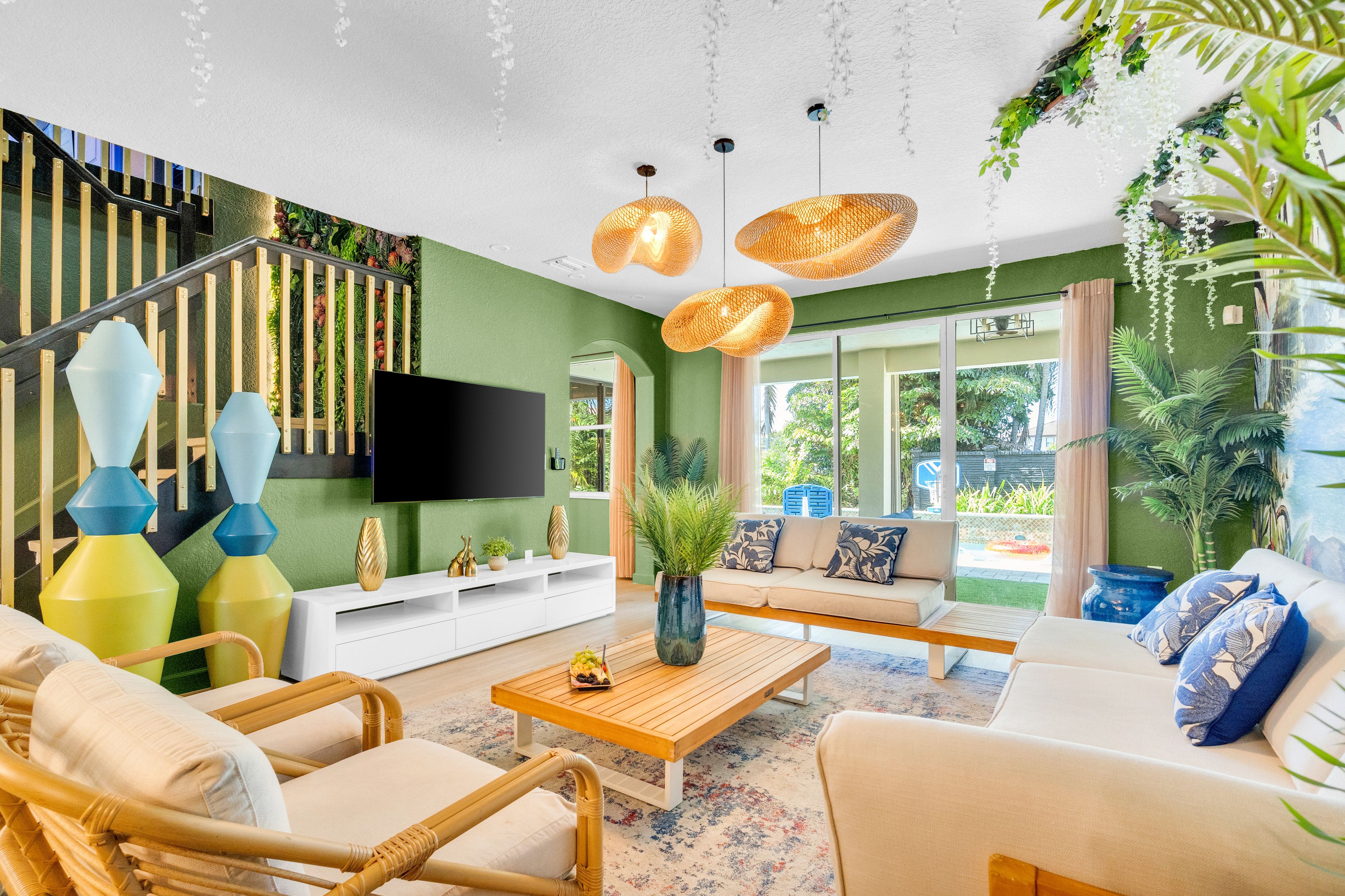 Sala de estar moderna com escada, televisão de tela plana e uma grande janela com vista para o verde.