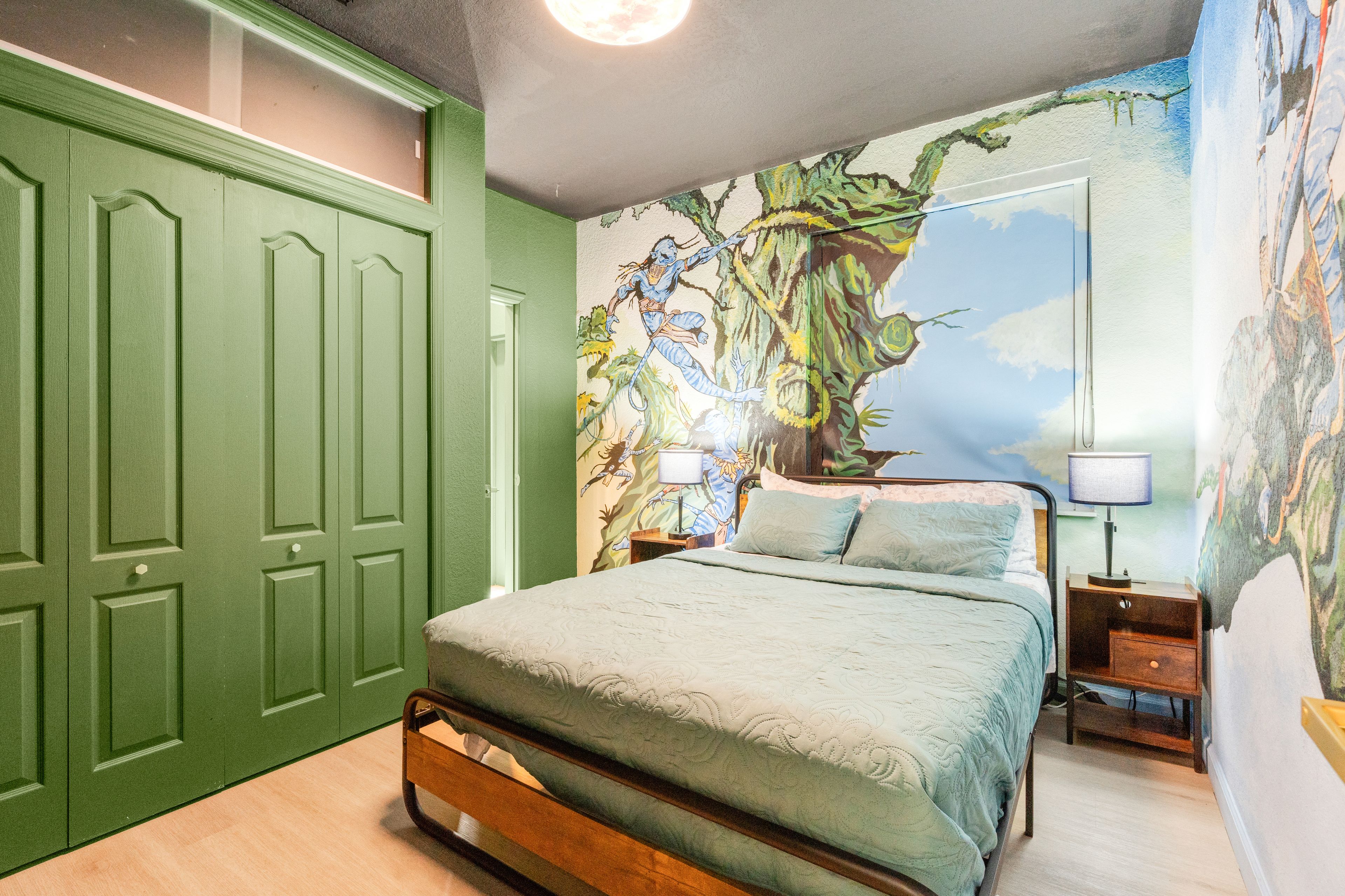 Un dormitorio con una cama, una mesita de noche, una lámpara y un armario verde.