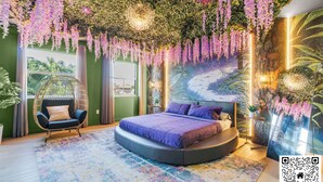 Quarto com cama redonda, cadeira suspensa e um mural florestal.