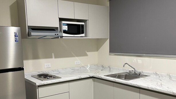 A modern kitchen with white cabinets, a built-in microwave, a stainless steel refrigerator, a black dining table, and a marble countertop. - Double Suite- 500m from "La Lomita". (Culiacán Rosales)