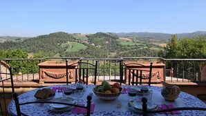 Une table dressée à l’extérieur, offrant une vue panoramique sur des collines et des arbres.