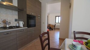 Une cuisine moderne équipée d’une cuisinière, d’un four et de placards, qui donne sur un coin repas avec une table mise pour deux personnes.