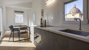 A modern kitchen with a built-in island, a dining area with chairs, a window with a view of a dome, and a wall-mounted light fixture.