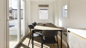 A modern kitchen with a wooden table, black chairs, and a window with a view.
