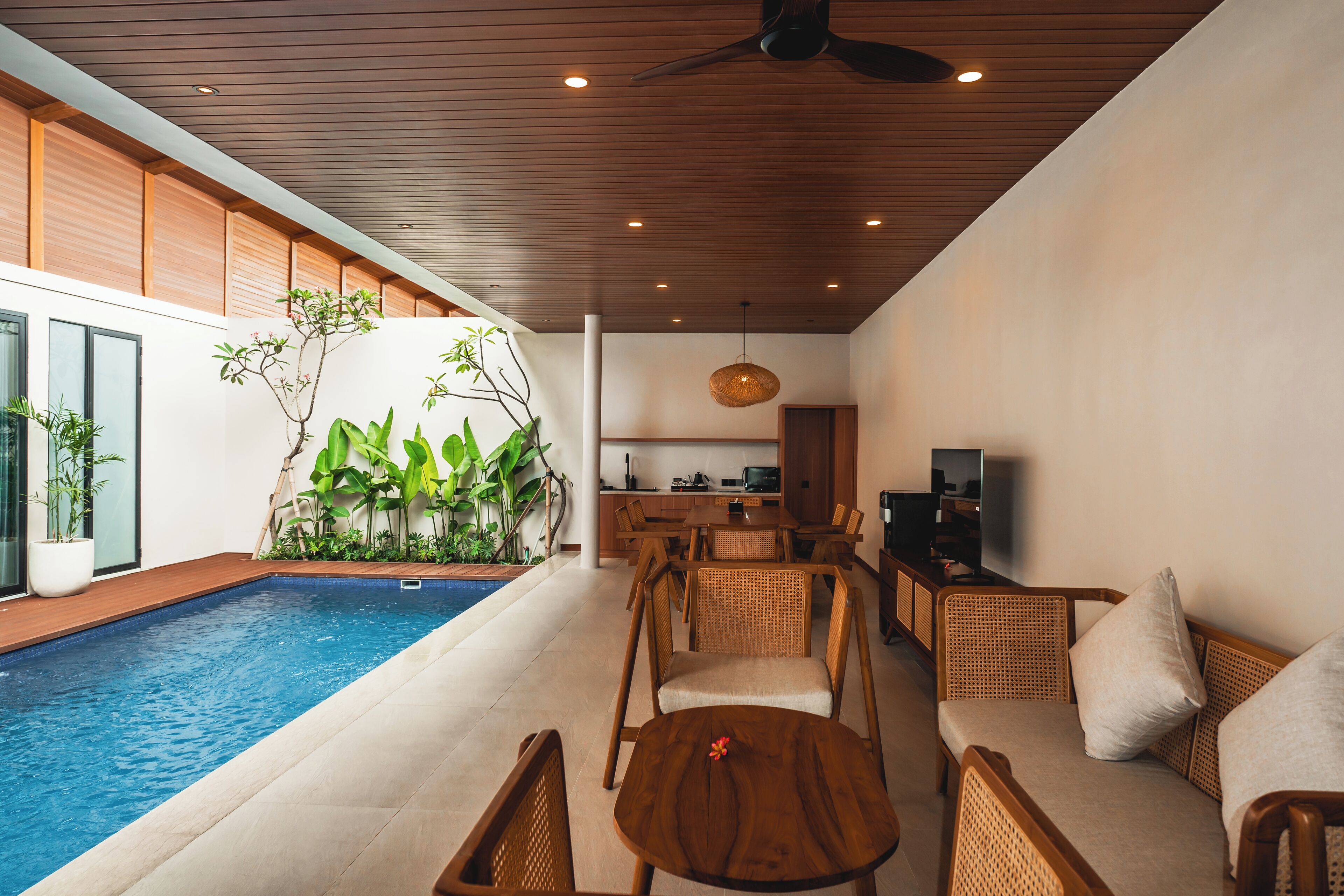 A modern indoor pool area with a dining area and kitchen.