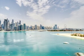A coastal cityscape with modern skyscrapers, a sandy beach, and a clear blue sea.