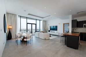 A modern living room with a dining area, a sofa set, a TV, and a kitchen island.
