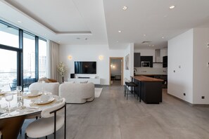 A modern living room with a dining area, a kitchen, and a TV mounted on the wall.