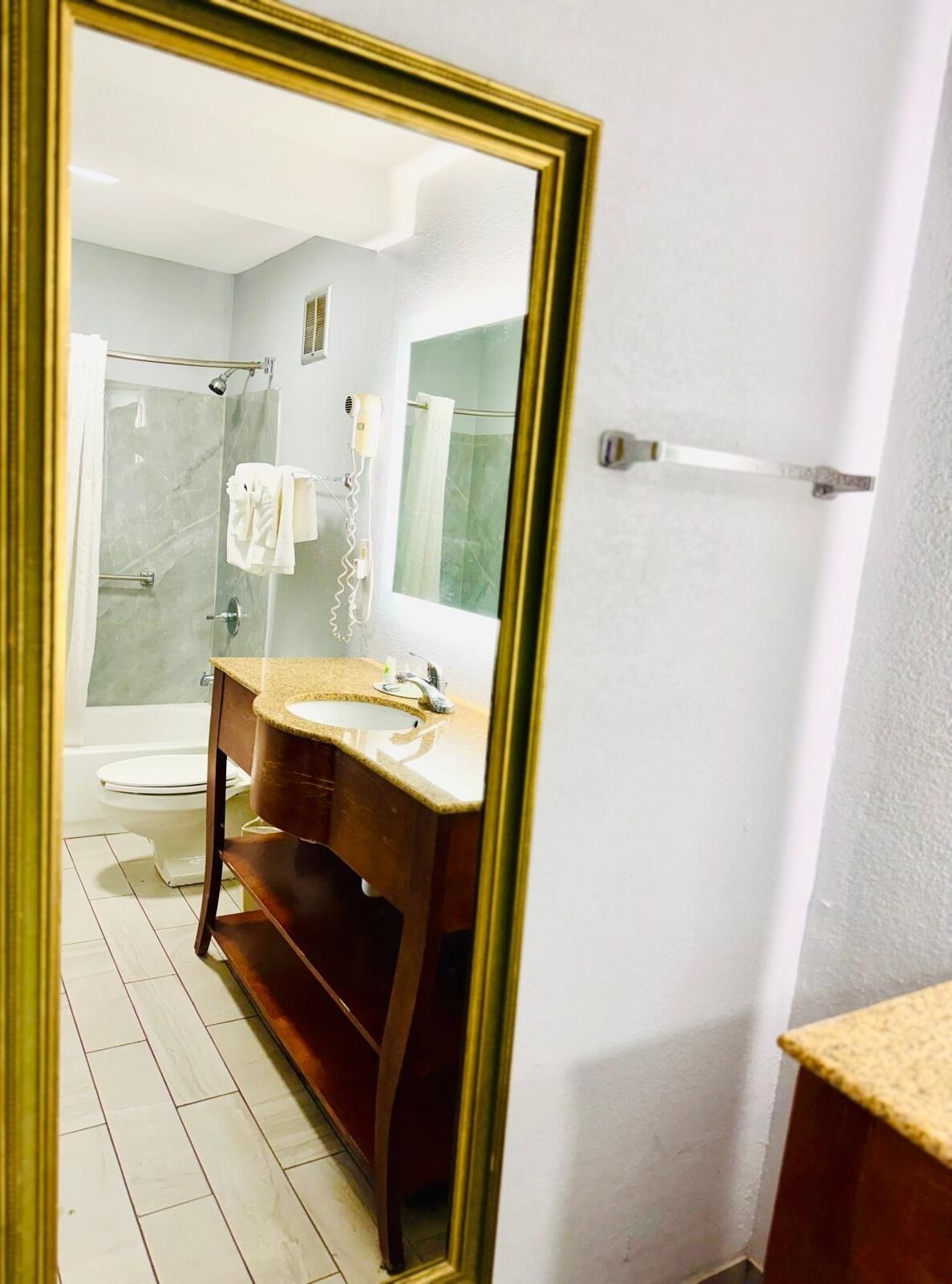 Un baño con tocador de madera, cabina de ducha de vidrio y inodoro blanco.