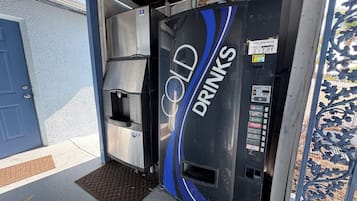 Un distributeur automatique portant l’inscription « BOISSONS FRAÎCHES » et proposant un choix de boissons, notamment du Pepsi, du Sprite et du Coca-Cola.