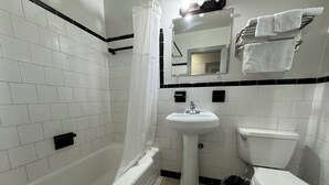Une salle de bain avec une baignoire, un lavabo, des toilettes et un miroir.