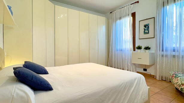 A bedroom with a large bed, a bedside table, a mirror, and a window with curtains. - Ca' de le Chiovere (Cannaregio) (Venecia)