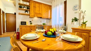 A dining area with a wooden table set for four, surrounded by wooden cabinets and a kitchen in the background. - Ca' de le Chiovere (Cannaregio) (Venecia)