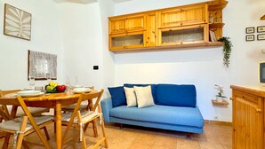 A dining area with a wooden table and chairs, a blue sofa, and wooden cabinets above. - Ca' de le Chiovere (Cannaregio) (Venecia)