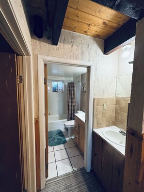 Un pasillo estrecho que conduce a un baño con bañera, inodoro y lavamanos.