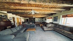 A spacious living room with a large sectional sofa, a wooden coffee table, and a ceiling fan. - Welcome to Crane Meadows, West Yellowstone Cabin, sleeps 32 close to Hebgen Lake (West Yellowstone)