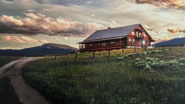 A rustic log cabin with a porch, surrounded by a fenced field and a dirt road. - Welcome to Crane Meadows, West Yellowstone Cabin, sleeps 32 close to Hebgen Lake (West Yellowstone)