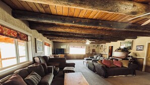 A rustic living room with wooden beams, a large sofa set, a wooden coffee table, and a television. - Welcome to Crane Meadows, West Yellowstone Cabin, sleeps 32 close to Hebgen Lake (West Yellowstone)