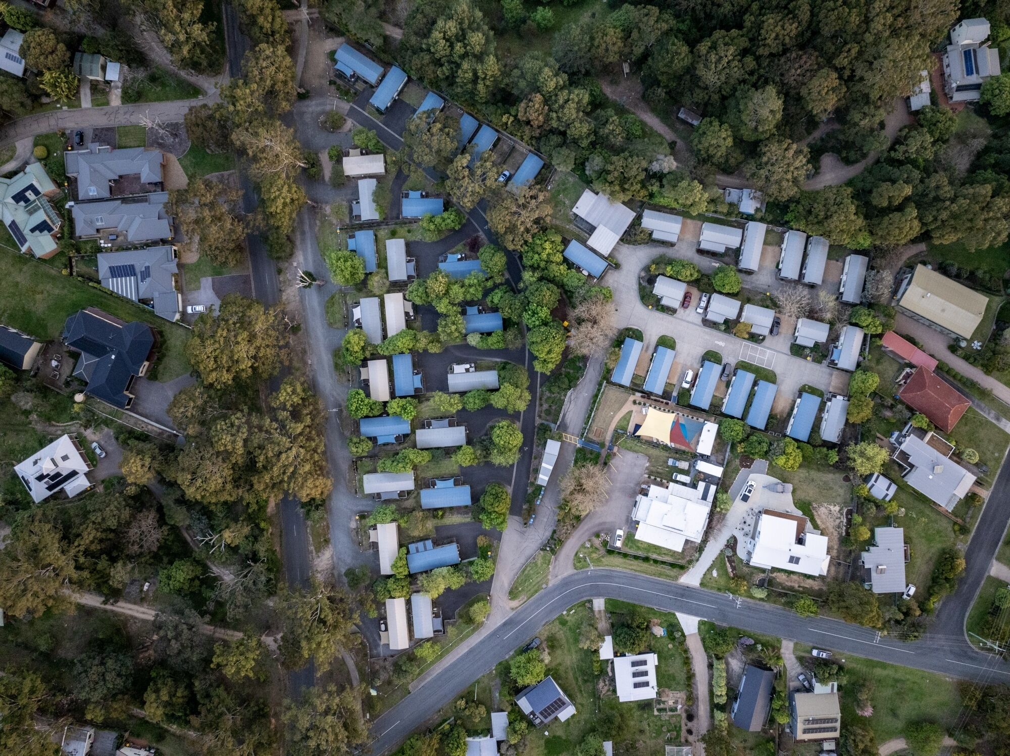 An aerial view of a residential area with multiple detached houses, roads, and green spaces.