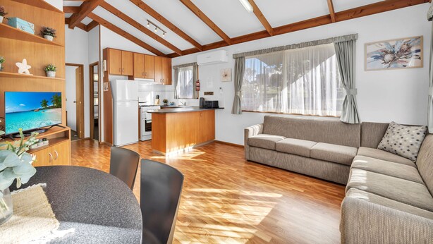 A spacious living area with a wooden ceiling, a sofa, a dining table, and a kitchen area. - 2 Bedroom Superior Villa (Metung)