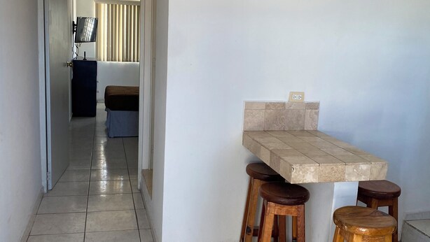 Una cocina con suelo de baldosas, una encimera y taburetes de madera.