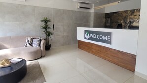 A modern reception area with a 'WELCOME' sign, a sofa, a potted plant, and a round coffee table. - RT properties at Belrose Place (Accra)