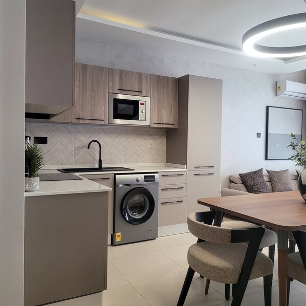 A modern kitchen with built-in appliances, a washing machine, and a dining area with a table and chairs.