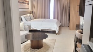 A modern hotel room with a large bed, a sofa, a round coffee table, and a TV. - RT properties at Belrose Place (Accra)