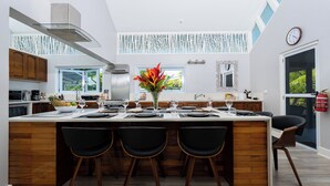 Una cocina moderna con una isla central, armarios de madera y un amplio ventanal.