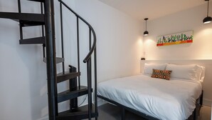 A bedroom with a bed, a black spiral staircase, and a wall-mounted artwork. - **Cleaning Fee Included** Mini modern cabin nestled in the peaceful hills between Jackson and Putnam County, minutes away from CUMMINS FALLS STATE PARK. Designed for comfort and style, this vacation rental seamlessly blends modern charm with wooded s (Cookeville)