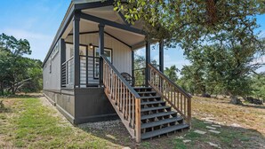 A small cabin with a wooden staircase leading to a porch. - Hidden Fox Escape - Grey Fox (Hays County)