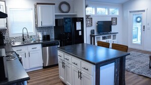 A modern kitchen with white cabinets, stainless steel appliances, and a central island.