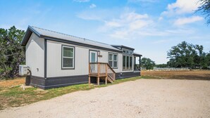 A single-story mobile home with a covered porch and a small wooden staircase.