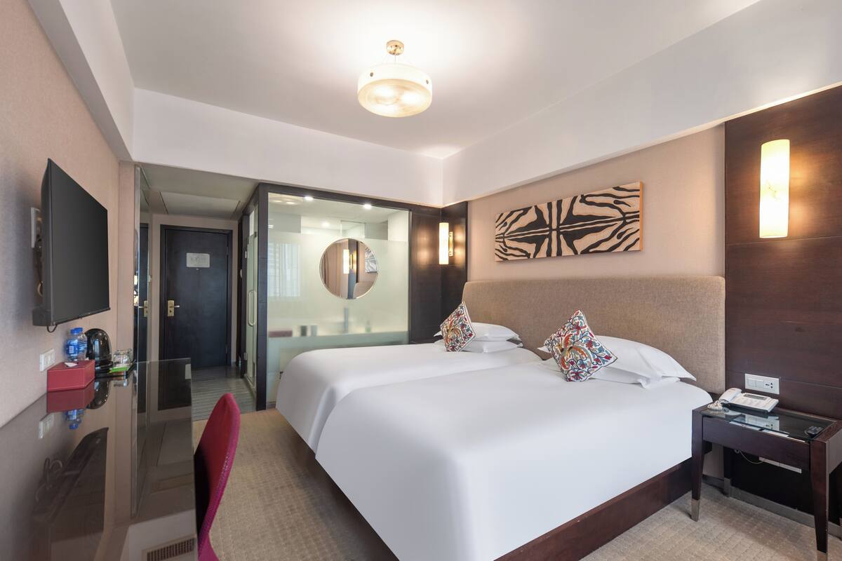 Ein Hotelzimmer mit einem großen Bett, einem Schreibtisch mit Stuhl, einem Fernseher und einem Spiegel.